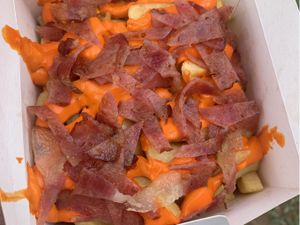 Porção de fritas com muito cheddar e bacon